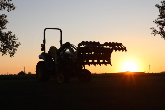 Compact Tractor with Grapple at Sunset